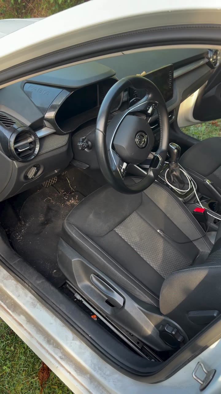 Habitacle de la Skoda Fabia avant nettoyage : tapis conducteur avec débris et seuil de porte poussiéreux