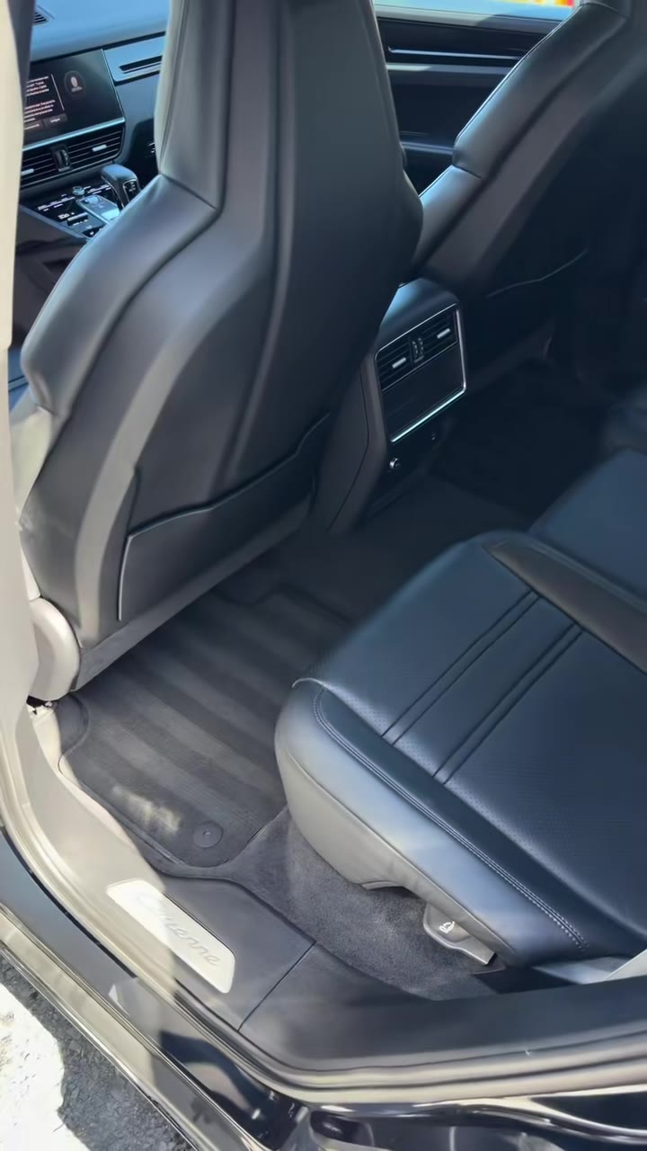 Places arrière d'une Porsche Cayenne : assise en cuir noir, tapis de sol et seuil de porte propres